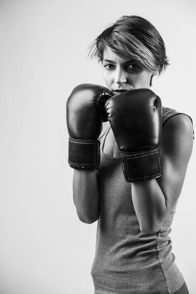 beautiful girl with bob hair and boxing gloves holds gurdia high, isolated on white background, black and white  - Fotografie, Obrázek