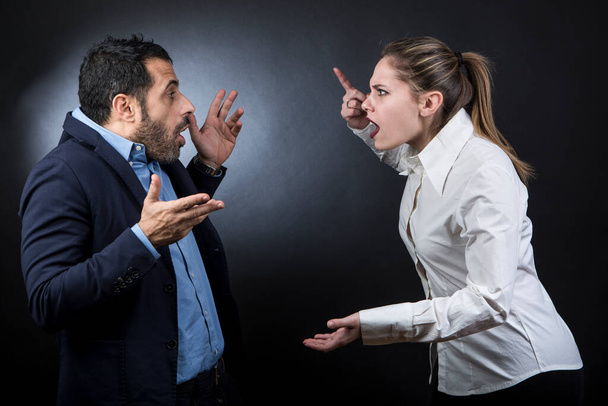 Couple argues, the girl accuses the boy by pointing her finger - dark background - Foto, imagen