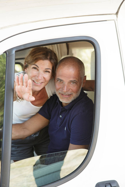 couple of gentlemen greets happy from the window of their camper car - Photo, Image