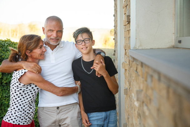 familie van drie gelukkige mensen knuffelt elkaar in de achtertuin - Foto, afbeelding