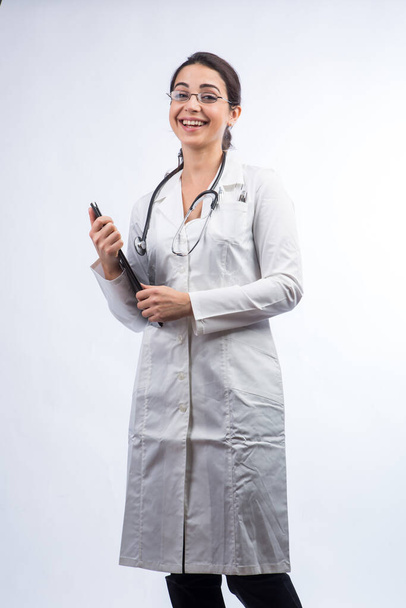 Біла жінка-лікар з чорним волоссям у білій шубці, окулярах та стетоскопі на шиї ізольована на білому тлі
 - Фото, зображення