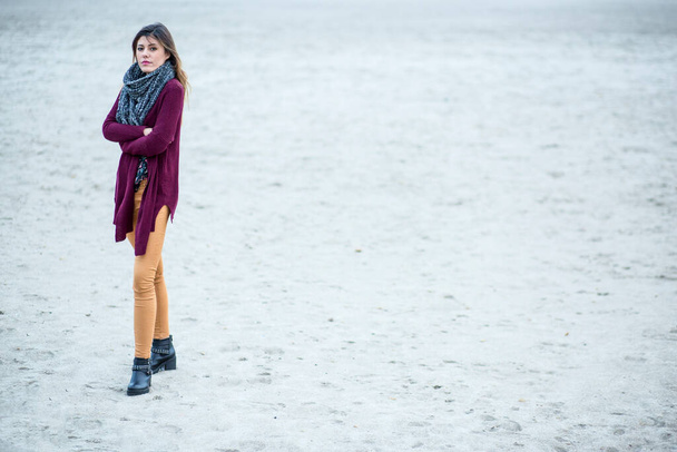 Beautiful brunette girl, with amaranth colored sweater and neck scarf at the beach - Photo, Image