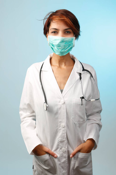 Cerrahi maskeli kadın doktor açık mavi arka planda izole edilmiş. - Fotoğraf, Görsel