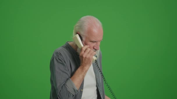 Groen scherm. Een oude man met een grijze baard praat op een vintage telefoon en ruzies met iemand. Het verzamelen en bewaren van oude telefoons. - Video