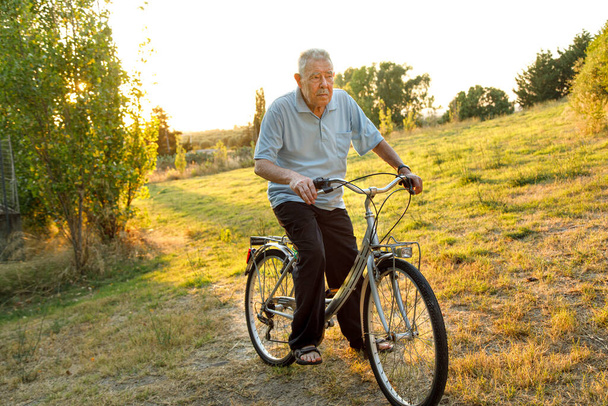 senior man riding bicycle on the road, lifestyle people concept - Photo, Image