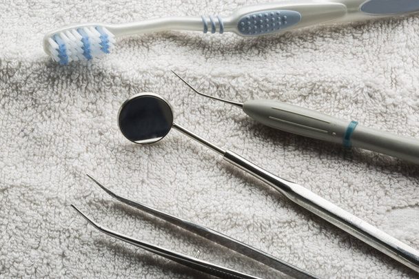 различные стоматологические инструменты, размещенные на белом полотенце - Фото, изображение
