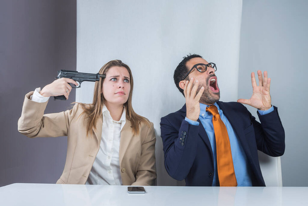 Девушка, сидящая в офисе, направляет пистолет на свой храм, пока ее босс говорит и кричит в небо - Фото, изображение