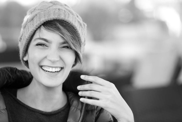 portret van mooi lachend meisje met pet en jas, zwart en wit  - Foto, afbeelding