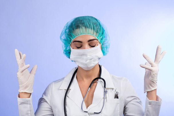 Female doctor in white coat, white face mask, green hair cap shows latex gloves before the operation, isolated on white background - Фото, изображение