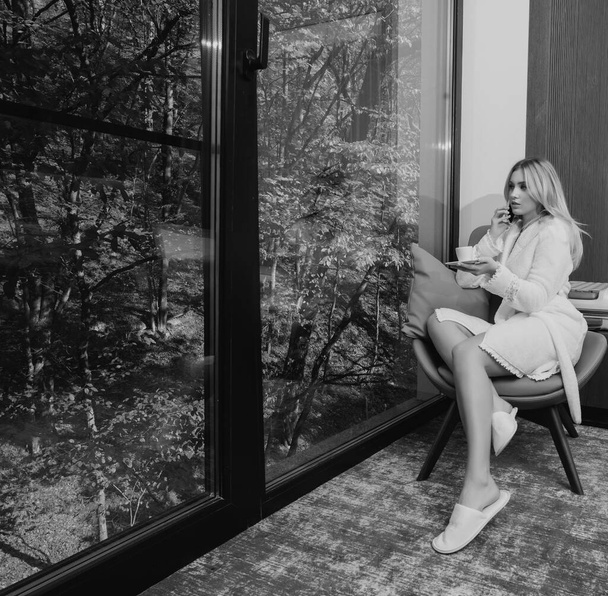 Beautiful woman drinking coffee in the morning sitting by the window. Relax at home. Morning coffee for sensual girl - 写真・画像