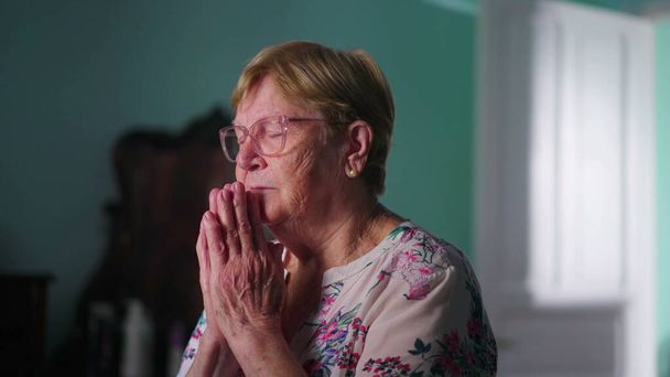 Reményteli vallásos idősebb nő Imádkozik Istenhez a hálószobában, úgy érzi, csatlakozik egy magasabb hatalom és elkötelezett az imádságban - Fotó, kép