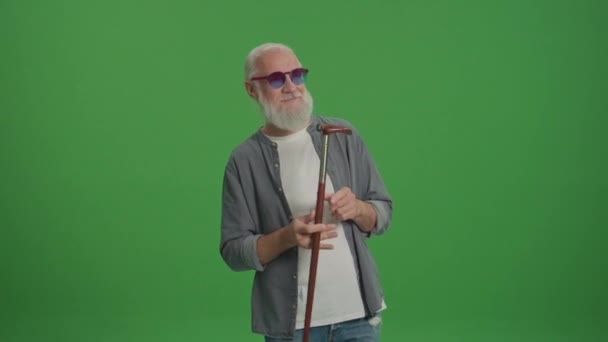Zöld vászon. Egy boldog öregember vicces szemüvegben, aki bottal táncol. Mosolygó Idős Ember Élvezze az életét. A modern idősek koncepciója. Nyugdíjba vonulás élvezetekkel és aggodalom nélkül. - Felvétel, videó