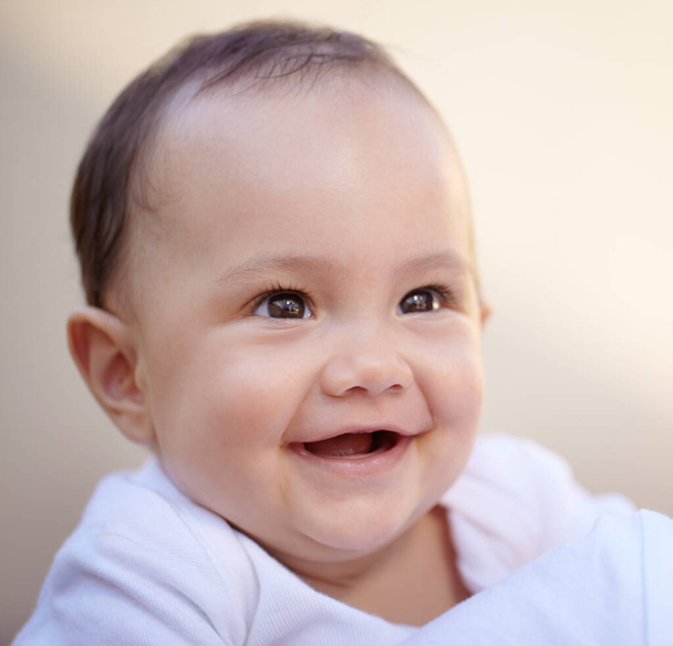 Ευτυχισμένο, κοντινό πρόσωπο ενός μωρού με χαμόγελο και ευεξία για την ανάπτυξη της παιδικής ηλικίας. Ευτυχία ή ενθουσιασμένοι, παιδική ηλικία ή χαχανητά για διασκέδαση και νήπιο χαμογελώντας για την υγειονομική περίθαλψη με γέλιο για κωμωδία. - Φωτογραφία, εικόνα