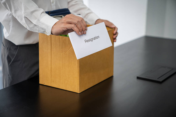 辞任の手紙と梱包を送るビジネスマンスタッフの辞任またはオフィスで机によってビジネス段ボール箱を運ぶ。会社からの転職・解雇. - 写真・画像