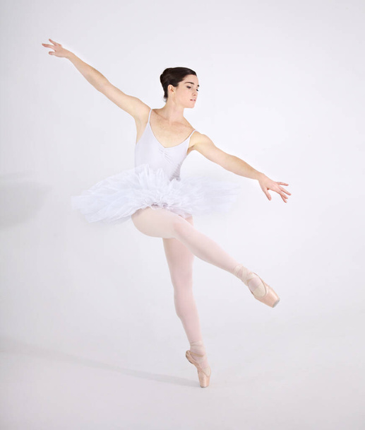 Elegance, dance and ballet with a woman in studio on a white background for rehearsal or recital for theatre performance. Art, creative and balance with a classy young ballerina or dancer in uniform. - 写真・画像