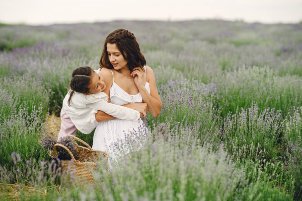 Mother with little daughter on lavender background. Beautiful woman and cute baby playing in meadow field. Family holiday in summer day. - Fotografie, Obrázek