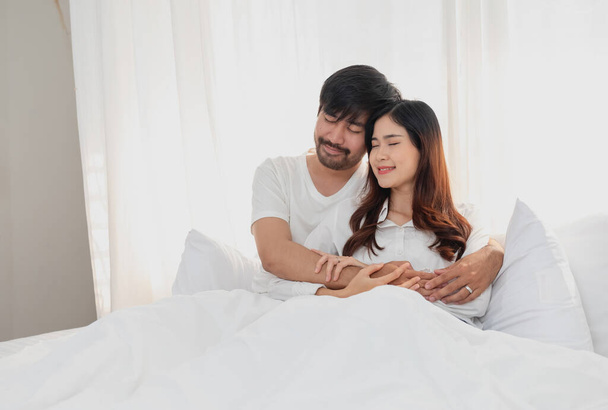 Happy young asian couple embracing, teasing, playing cheerfully in bed at home, romantic time to enhance family bonding. family concept. - Zdjęcie, obraz