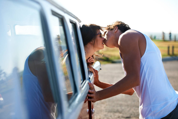 Kiss, love and a couple on a road trip in a van for a holiday, adventure or a drive. Care, romantic and a man and woman kissing in nature with transportation for a honeymoon vacation or date. - Foto, afbeelding