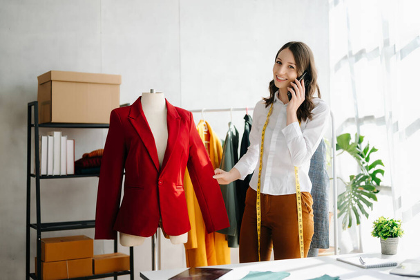 Caucasian young woman,fashion designer with phone and tablet pc in office - 写真・画像