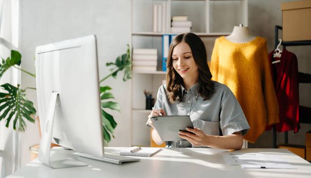 Young business owner woman  checking online orders for deliver to customer with tablet and laptop. Shopping Online concept. in office - Foto, Imagen