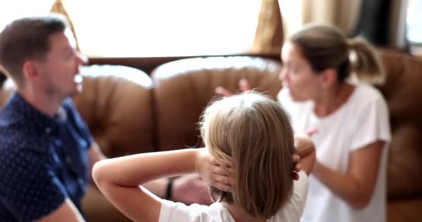 Rear view of child girl covers ears with hands while parents are quarreling. Child suffering from parental quarrels neglect or divorce - Záběry, video