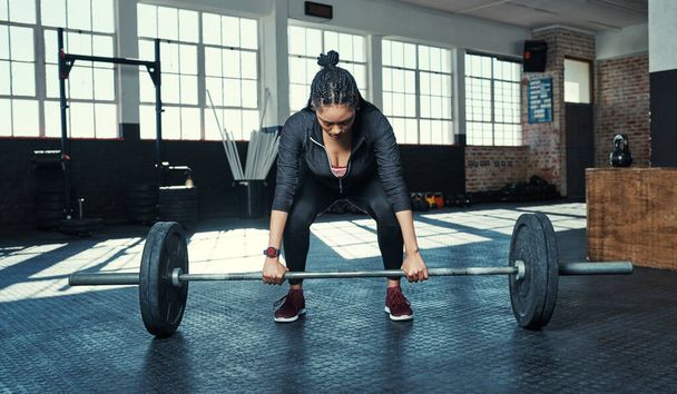 Lifting for strength. a young woman lifting weights in a gym - Фото, изображение