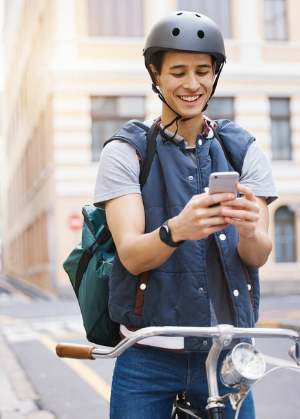 Man, delivery bicycle and smile with phone, order or ecommerce app for food, product and sustainable transport. Young guy, bike and metro street with texting, chat and eco friendly with logistics job. - Photo, Image