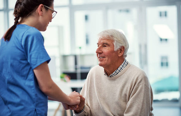 Hij weet dat hij in goede handen is. een jonge vrouwelijke verpleegster in gesprek met haar oudere patiënt in het bejaardentehuis - Foto, afbeelding