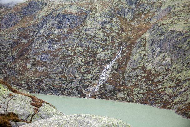 Гірський ландшафт з озером, водоспадом і швейцарськими горами. Захоплює красу, спокій і благоговіння. Пристойні води відображають величне середовище.. - Фото, зображення