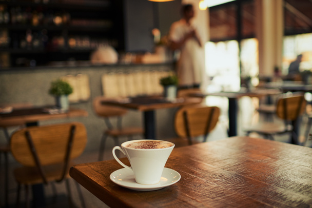 Ξύλινο τραπέζι, κούπα καφέ και καφέ κατάστημα, εστιατόριο ή εστιατόριο για το εμπόριο ποτών, ποτών ή λιανικής υπηρεσιών αγορών. φλιτζάνι τσάι, πρωινό espresso ή startup μικρή επιχείρηση για πωλήσεις φρέσκιας καφεΐνης. - Φωτογραφία, εικόνα