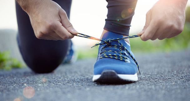 Shoes, hands and man tying shoelace for run, fitness outdoor for exercise, cardio and active with health and closeup. Sports, running sneakers and male person start workout with bokeh and training. - Photo, Image