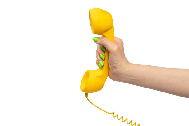 Yellow handset in woman hand with green nails isolated on a white background. Copy space. - Foto, immagini
