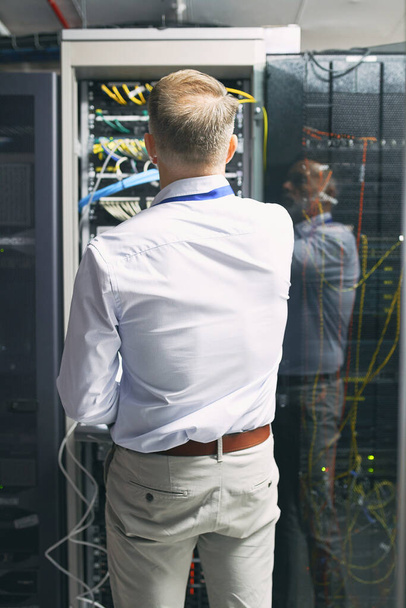 Connecting to the main server. Rearview shot of a mature man working in a server room - Foto, immagini