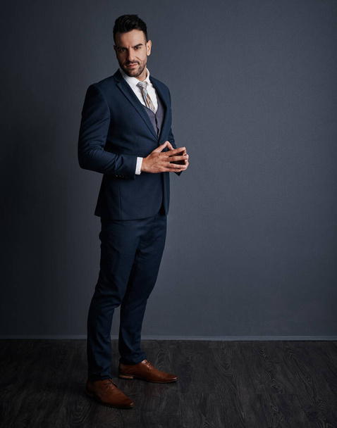 スタイリッシュなスーツよりも成功とは言えない。灰色の背景を背景にしたスタイリッシュな自信に満ちた若いビジネスマンのスタジオショット - 写真・画像