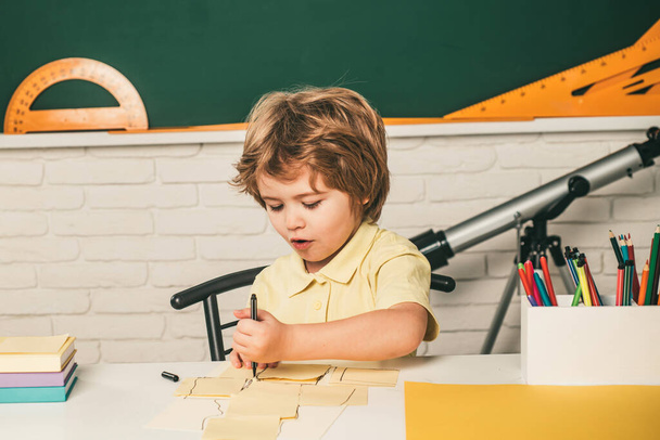 Schoolkid or preschooler learn. Cute pupil with funny face schooling work - Фото, зображення