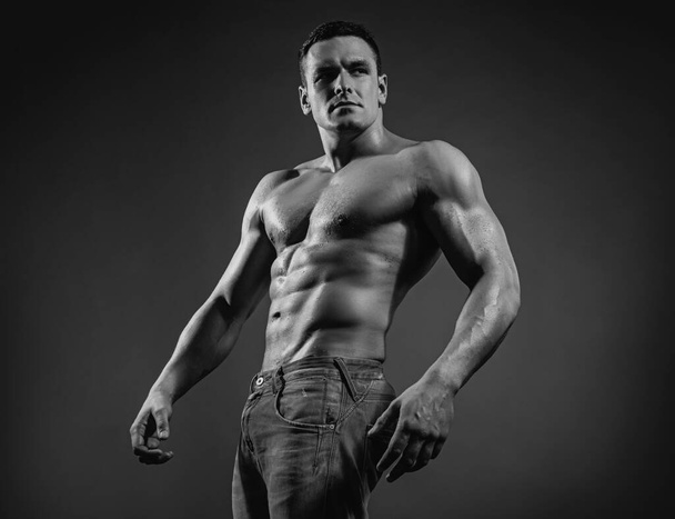 Portrait handsome sexy muscular man, athlete with perfect body over dark background. Sexy muscle strong face guy in jeans on gray studio isolated - Photo, Image