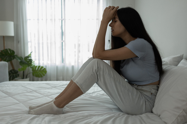 Female having depression sitting alone in bedroom corner. woman headache unhappy emotion. young anxiety despairing mental health problems. - Photo, Image