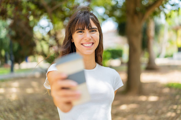 Young woman at outdoors holding a take away coffee with happy expression - Foto, afbeelding