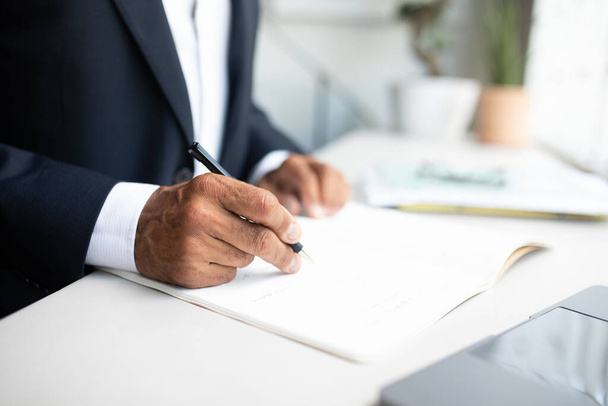 European senior ceo businessman in suit, signs contract with pen at table in office interior, cropped, close up. Work planning, business contract and create startup project - Foto, imagen