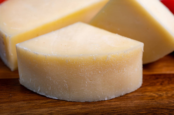 Olasz sajt, Provolone dolce tehénsajt Cremonából, olívapogácsával és paradicsommal tálalva, közelről. - Fotó, kép