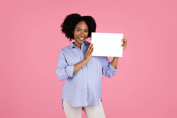 Positive young pregnant african american curly lady in casual with big belly show banner with copy space, isolated on pink background, studio. Motherhood, expect baby, sale, ad and offer - Foto, immagini