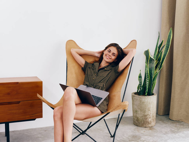 Žena na volné noze student sedí v křesle s notebookem práci doma úsměv a relaxovat, moderní stylový interiér skandinávský životní styl, kopírovací prostor. Kvalitní fotografie - Fotografie, Obrázek