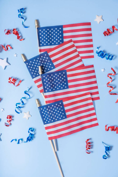 ΗΠΑ Ημέρα Ανεξαρτησίας έννοια. Σημαίες ΗΠΑ και κόκκινο και μπλε σπείρες και λευκά αστέρια πάνω άποψη, επίπεδη θέσει σε μπλε φόντο. - Φωτογραφία, εικόνα