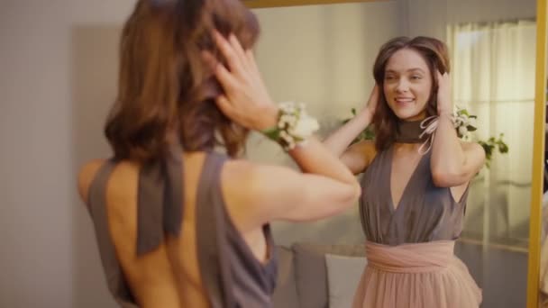 Back View of Pretty Young Woman Corrects Her Appearance in Front of the Mirror.An Attractive Girl Getting Ready for an Event, Prom. Feminidad y elegancia. Humor festivo. - Imágenes, Vídeo