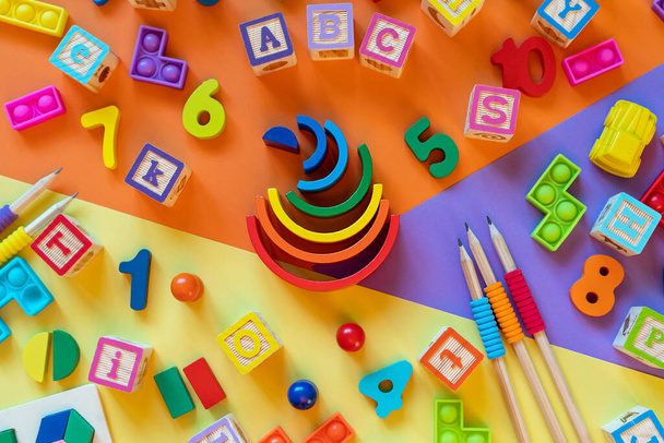 Brinquedos infantis de madeira em papel colorido. Brinquedos educativos blocos, pirâmide, lápis, números. Brinquedos para jardim de infância, pré-escola ou creche. Copiar espaço para texto. Vista superior - Foto, Imagem