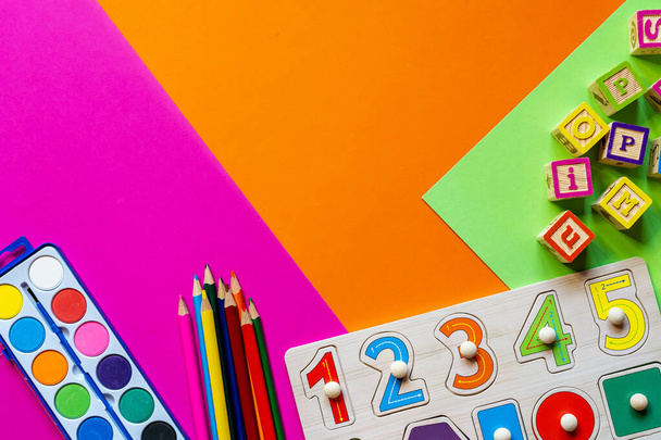 Giocattoli per bambini in legno su carta colorata. Blocchi di giocattoli educativi, piramide, matite, numeri. Giocattoli per l'asilo, la scuola materna o l'asilo. Copia spazio per testo. Vista dall'alto - Foto, immagini