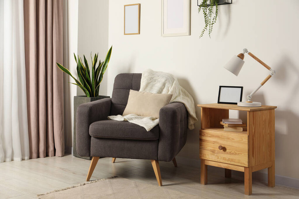 Cozy room interior with comfortable armchair, desk lamp and beautiful decor elements - Fotó, kép