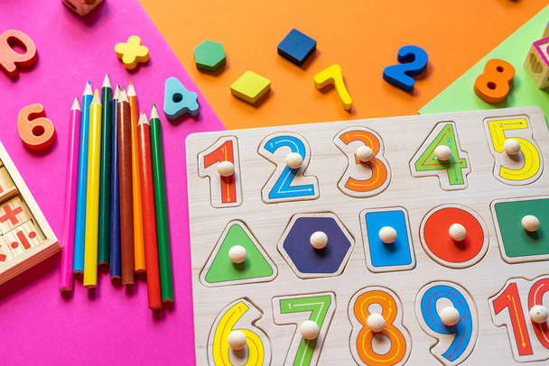 Wooden kids toys on colourful paper. Educational toys blocks, pyramid, pencils, numbers. Toys for kindergarten, preschool or daycare. Copy space for text. Top view - Photo, Image