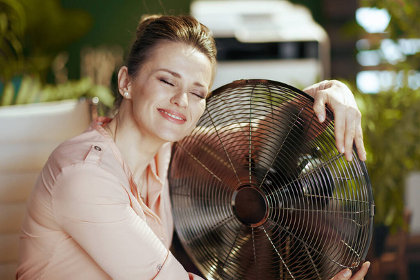 Sustainable workplace. smiling modern accountant woman in modern green office with electric fan. - Zdjęcie, obraz