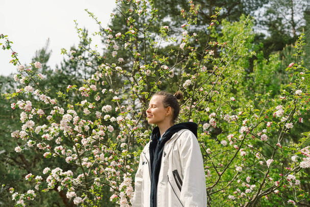 Kaunis nuori nainen kevään kukkia nauttia luonnosta ja nauraa kevätpuutarhassa. Nainen, jolla on omenapuun oksa. Vapauden ja onnellisuuden käsite. Kevät. - Valokuva, kuva